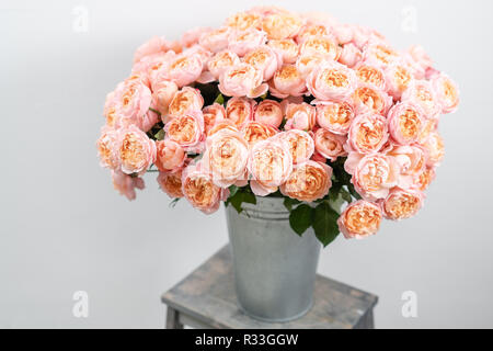 Großen Luxus helle Blumenstrauß peony Rose auf Holztisch. Garten spray Rosen rosa und Pfirsich Farbe. Blumenstrauß in Vase aus Metall Stockfoto