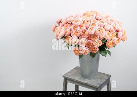 Großen Luxus helle Blumenstrauß peony Rose auf Holztisch. Garten spray Rosen rosa und Pfirsich Farbe. Blumenstrauß in Vase aus Metall Stockfoto