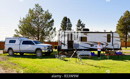 42,881.02545 Frau camper Reisenden stehen die RV camp Trailer und 3/4 Tonne Pickup truck Zugfahrzeug, in schön gemäht grünes Gras RV Park mit Bäumen Stockfoto