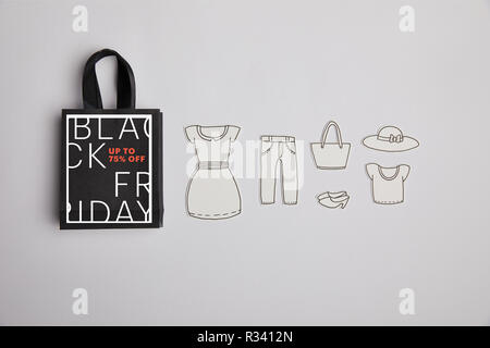 Blick von oben auf die Paper Bag mit schwarzer Freitag Verkauf Zeichen und Papier Kleidung auf grauem Hintergrund Stockfoto