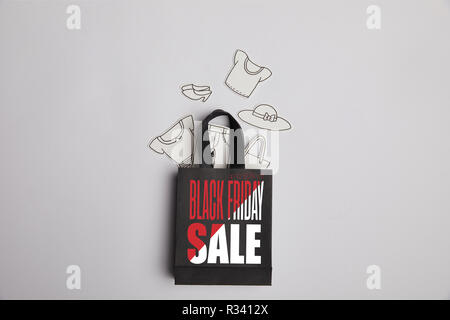Blick von oben auf die Paper Bag mit schwarzer Freitag verkauf Inschrift und Papier Kleidung auf grauem Hintergrund Stockfoto