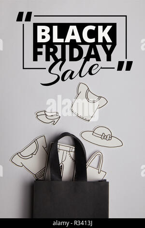 Ansicht von oben schwarz Einkaufstasche mit wertpapierabwicklungssystemen Inschrift und Papier Kleidung auf grauem Hintergrund, Shopping Konzept Stockfoto