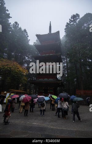 Toshogu Gojunoto, die fünf Geschichte rote Pagode am Eingang zum Toshogu in Nikko, Japan. Eine Gruppe von Touristen mit Sonnenschirmen betrachtet die Pagode. Stockfoto