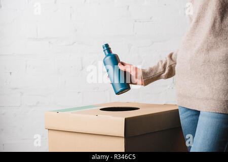 7/8-Ansicht von Frau werfen Plastikflasche in Papierkorb Stockfoto