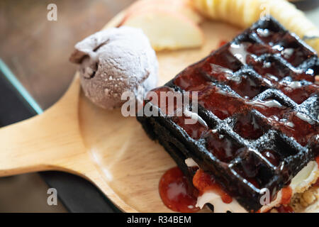 Close Up Black Charcoal Waffel mit Schokolade Eis auf Holz Schale im Cafe, süßes Dessert Bäckerei Konzept. Stockfoto