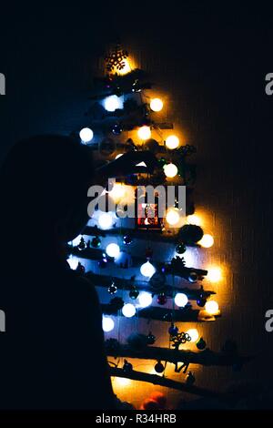 Weihnachten. Die Mädchen bewundert die helle, schöne Tanne aus der Sticks dekoriert mit schönen Girlanden aus Blau und Orange. Stockfoto