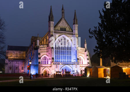 Die gotische Kathedrale von Winchester bei Nacht beleuchtet und Winchester Weihnachtsmarkt - beliebte Touristenattraktionen in der ehemaligen Hauptstadt von England Stockfoto