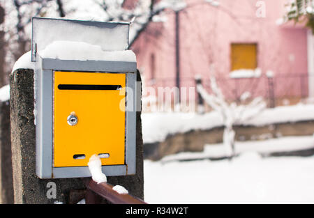 Schneebedeckte gelben Briefkasten vor einem Haus Stockfoto
