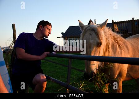 Ein junger Mann hängt heraus mit seinem Pferd Stockfoto