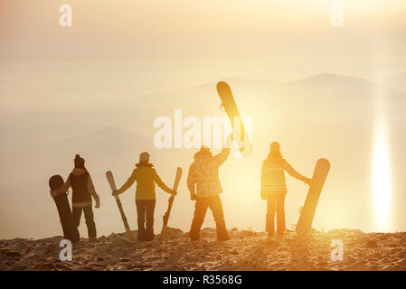 Gruppe von Skifahrern und Snowboardern bei Sonnenuntergang. Ski Resort Konzept Stockfoto