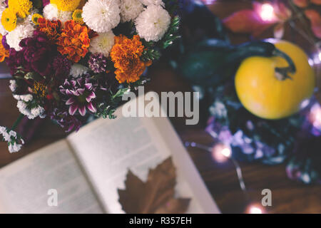 Blick von oben auf einen Blumenstrauß und offenes Buch auf dem Tisch Stockfoto