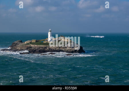 Godrevy Leuchtturm allein stehend auf der Insel vor der Küste von Cornwall als Warnung für die Schifffahrt. Durch Wellen und Felsen umgeben ist. Stockfoto