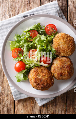 Karbonader paniertes Schwein Pastetchen Rezept mit frischen Salat close-up auf einem Teller auf den Tisch. Vertikal oben Ansicht von oben Stockfoto