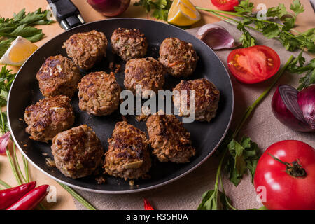 Essen im rustikalen Stil. Hausgemachte gebratenes Rindfleisch Frikadellen auf der Pfanne, mit Gemüse, über Holz Schreibtisch. Stockfoto