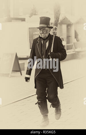 Schornsteinfeger geht die Straße hinunter.im Gloucester Quays Victorian Christmas Market, Gloucester, Gloucestershire im November - getönt für gealterte Wirkung Stockfoto