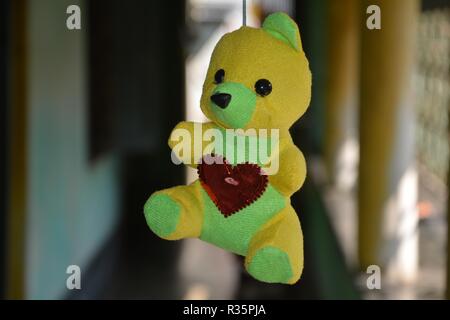 Eine ausgestopfte Puppe von teddy bear hanging in Gelb und Grün. Stockfoto