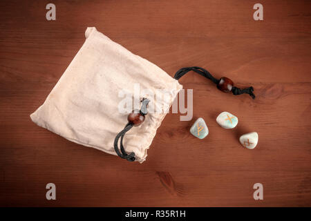 Nordischen Runen des Futhark Alphabet, Steine mit Symbolen in Wicca und andere Magie und für Weissagung benutzt, warf aus der Tasche auf einem dunklen Hintergrund Stockfoto