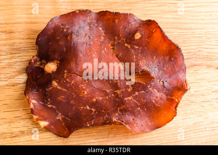 In dünne Scheiben geschnitten und getrocknet geräucherten Schinken auf Eiche Fach kleine Kristalle von Salz auf das Fleisch sichtbar. Stockfoto