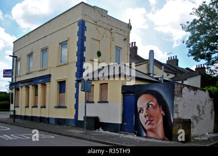 Ein street art Porträt einer jungen Frauen ziert die Rückseite eines geschlossenen öffentlichen Haus in Penge South London, UK. Stockfoto