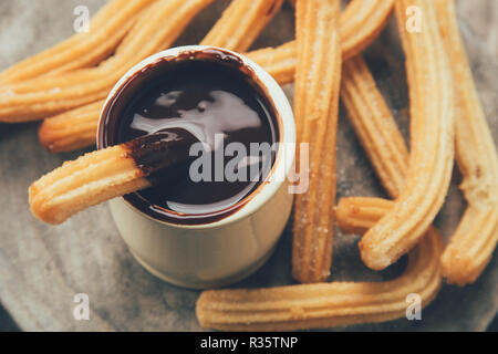 Traditionelle spanische Churros mit heißer Schokoladensauce auf einem rustikalen Holzmöbeln schicht. Ansicht von oben Stockfoto