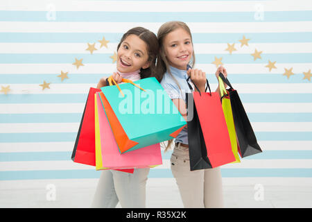 Die Kinder glücklich tragen Bündel Pakete. Einkaufen mit beste Freundin Konzept. Mädchen wie einkaufen. Die Kinder glücklich kleine Mädchen halten Einkaufstaschen. Viel Spaß beim Shoppen mit der besten Freundin oder Schwester. Mädchenhafte Glück. Stockfoto