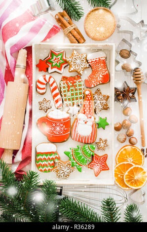 Urlaub essen Hintergrund. Gingerbread cookies mit Cutter, nudelholz und Zutaten zum Backen auf weissem Holztisch. Ansicht von oben. Stockfoto