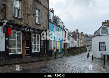 Ein Pub und bunten Reihenhäuser entlang eines gepflasterten Straße in South Queensferry, Edinburgh. An einem regnerischen Tag. Stockfoto