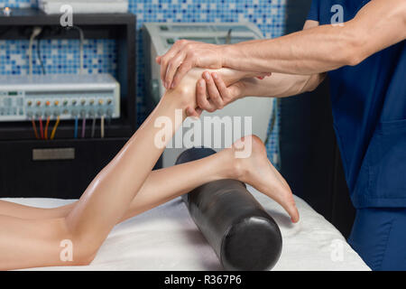 Ansicht von der Seite des Prozesses der Massieren der Füße der weiblichen Klienten in Spa Kosmetik salon. Masseur, Massage mit muskulöse Hände, junge Frau. Konzept der Körperpflege und entspannende Verfahren. Stockfoto