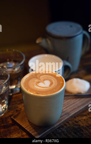 Zwei Tassen Kaffee und ein Glas Wasser auf rustikalen Holztisch. Close-up. Stockfoto