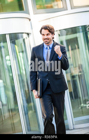 Attraktive junge Geschäftsmann Jubel vor einem Geschäft Gebäude Stockfoto