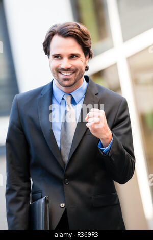 Attraktive junge Geschäftsmann Jubel vor einem Geschäft Gebäude Stockfoto