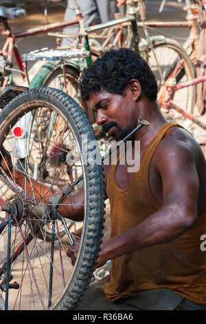 Chennai, Indien - 5. September 2007: Ein indischer Mann nutzt einen Schraubenschlüssel, um die Schraube auf dem Rad eines Fahrrades, in die Stadt zu ziehen - Zentrum von Chennai. Stockfoto