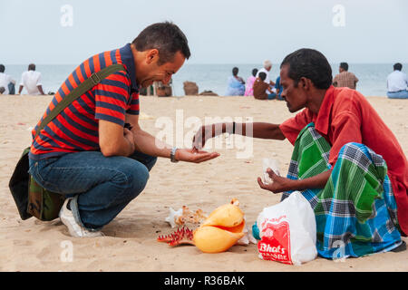 Chennai, Indien - 6. September 2007: ein Tourist kauft Koralle Perlen von einem lokalen Verkäufer in der beliebten Marina Beach in Chennai an einem heißen Nachmittag. Stockfoto