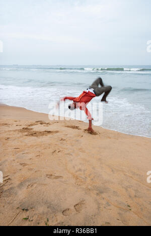 Chennai, Indien - 6. September 2007: Aman führt einen Purzelbaum in der Nähe von den brechenden Wellen vom rauhen Meer bei Marina Beach in Chennai. Stockfoto