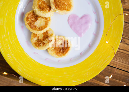 Lecker Käse Pfannkuchen auf gelbem Teller stehen auf einem Holzbrett - Tag in Liebe, Frühstück im Bett. Stockfoto