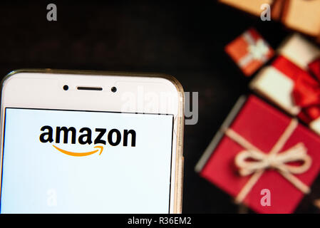 Die amerikanische Electronic Commerce und Cloud Computing Unternehmen Amazon Logo ist auf ein Android mobiles Gerät mit Weihnachten gesehen Gaben im Hintergrund gewickelt. Stockfoto