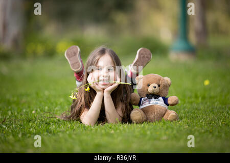 Lächelnde Mädchen im Park mit Teddybär Stockfoto
