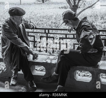 Schwarz-weiß Foto von zwei älteren chinesischen Kollegen spielen beliebte Spiel von mah-jong in chinesischen Parks. Kunming in China. Stockfoto