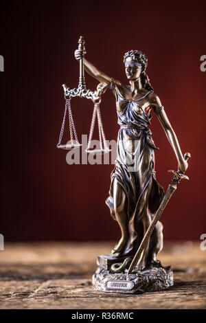 Lady "Justicia mit Schwert und Waage Bronze Figur auf hölzernen Tisch. Stockfoto