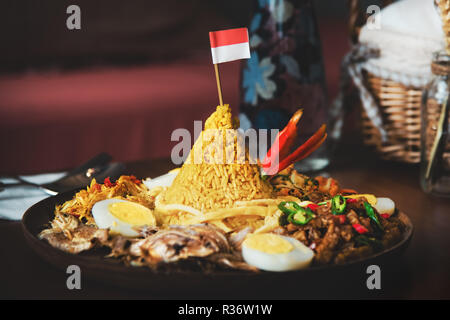 Traditionelle indonesische Küche Nasi Tumpeng für die Unabhängigkeit feiern mit Flagge. Tumpeng ist ein kegelförmiges Reisgericht mit Fleisch wie Berg Stockfoto