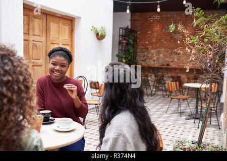 Weibliche Freunde plaudern über Getränke in einem angesagten Café Hof Stockfoto