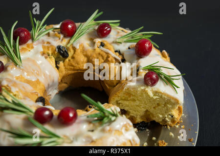 Handmade Christmas Cake mit Garnierung von Cranberry und Rosmarin auf Dunkel. Close Up. Stockfoto