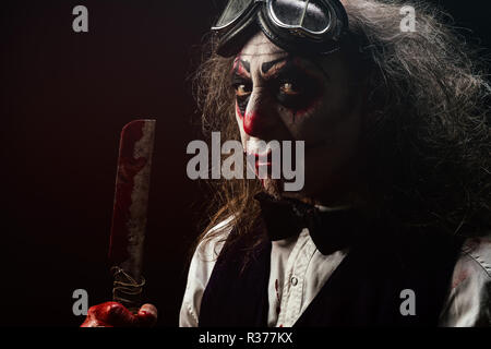 Porträt eines sadistischen Clown, ein blutiges Messer in seiner Hand. Stockfoto