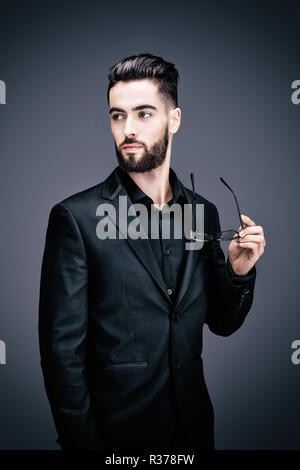 Portrait einer jungen Geschäftsmann Holding eine Brille, auf der Suche auf der Seite Stockfoto