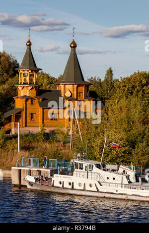 "Tserkov Uspeniya Presvyatoy Bogoroditsy. Neu Holzkirche auf dem Moskauer Canal, Moskau, Russland gebaut. Barge angedockt am Steg. Stockfoto