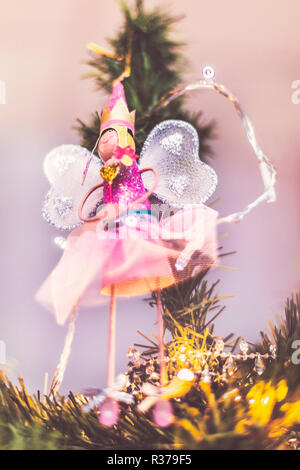 Pretty fairy angel Dekoration hängen von der Spitze des einen Weihnachtsbaum. Sie hat sparkly net Flügel und ist eine Krone trägt. Es gibt Lichterketten aroun Stockfoto