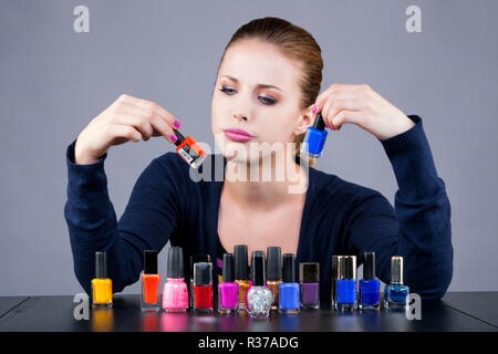 Dilemma einer jungen Frau vor Nagellack Stockfoto