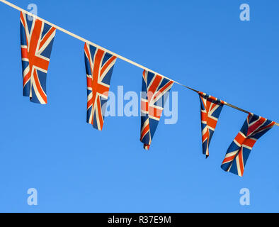 Reihe kleiner Union Jack Fahnen im Wind flattern vor einem tiefblauen Himmel. Stockfoto