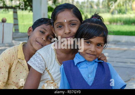 Drei junge indische Geschwister, einen Jungen, zwei Mädchen, posieren für die Kamera irgendwo in Ranganatha, Anegundi, Karnataka, Indien Stockfoto