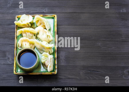 Chinesische Küche Teller - Serviert Teil der Knödel mit drei Füllungen (Garnelen, Ei, grüne) auf Platte auf dunklen Holzplatte mit Copyspace Stockfoto